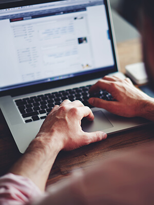 Cropped image of a young man working on his laptop in a coffee shop, rear view of business man hands busy using laptop at office desk, young male student texting on computer sitting at wooden table